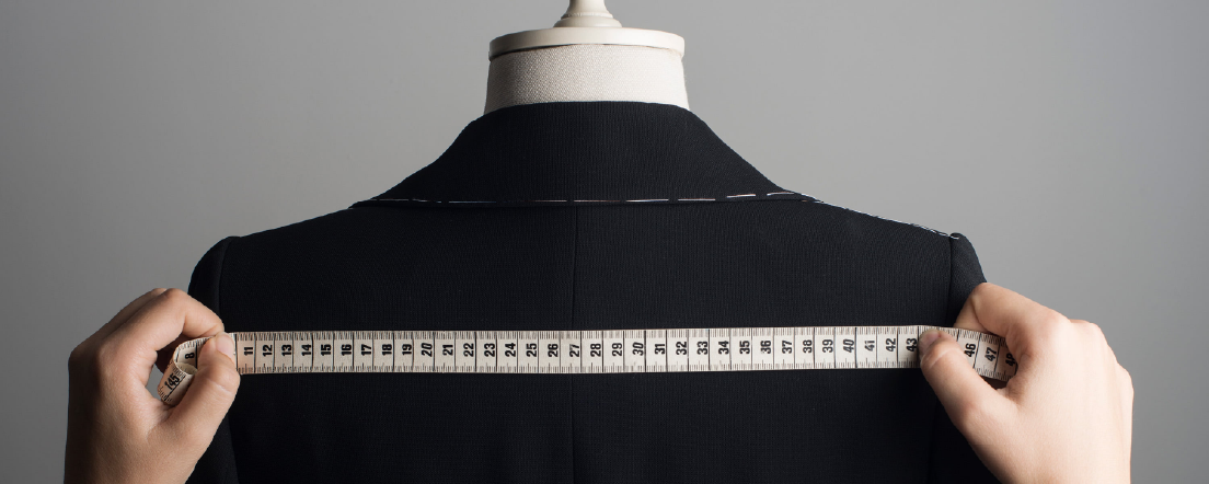 Des mains tenant un ruban à mesurer autour des épaules d’un mannequin