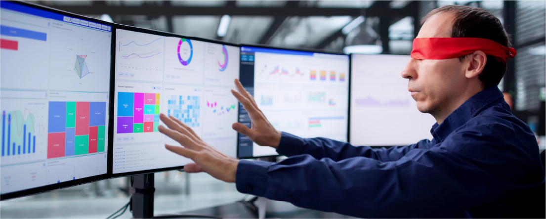 Man wearing a red blindfold reaching his arms toward several computer monitors displaying various charts and graphs