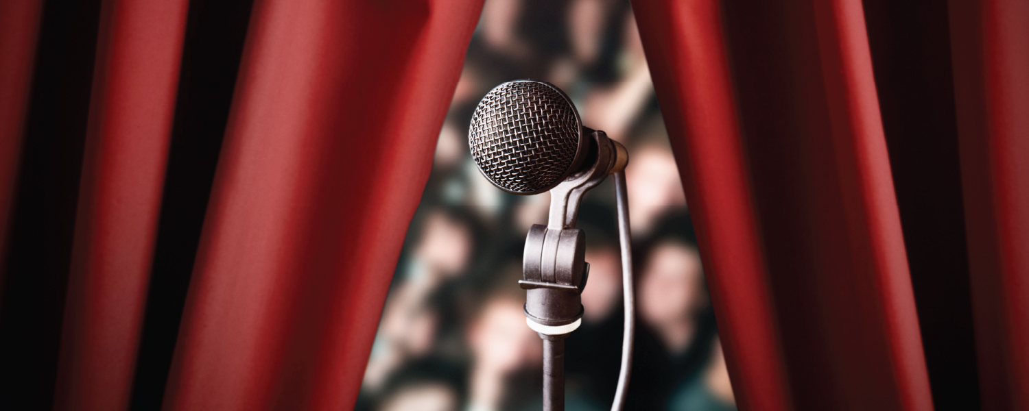 Microphone devant un public et un rideau rouge